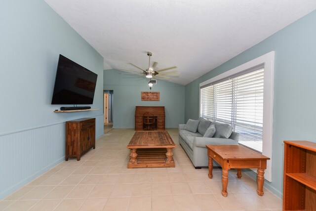 living room with ceiling fan, a fireplace, and vaulted ceiling