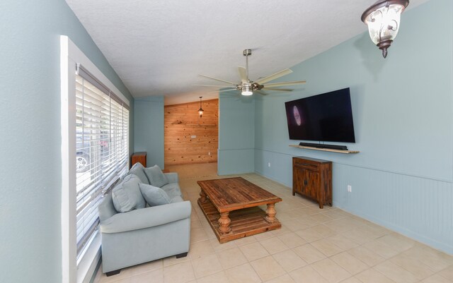 living room with vaulted ceiling, wooden walls, a textured ceiling, and ceiling fan