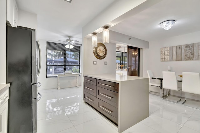 kitchen with stainless steel refrigerator, white cabinetry, ceiling fan, decorative light fixtures, and dark brown cabinets