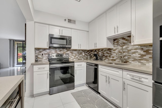 kitchen featuring white cabinets, appliances with stainless steel finishes, light tile patterned floors, and sink