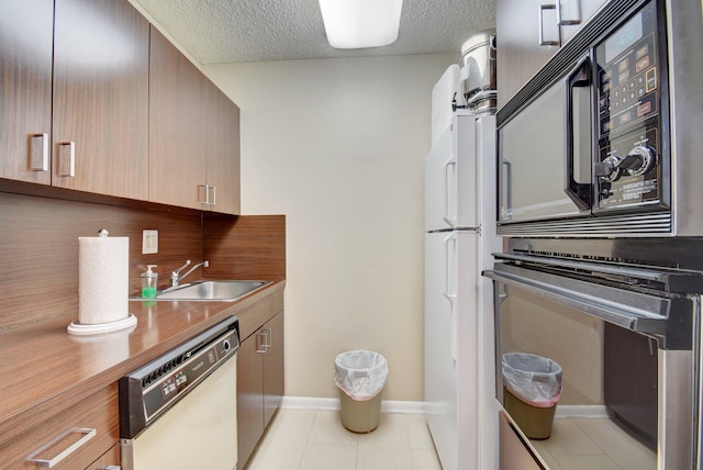 kitchen featuring sink, stainless steel dishwasher, white fridge, a textured ceiling, and black oven