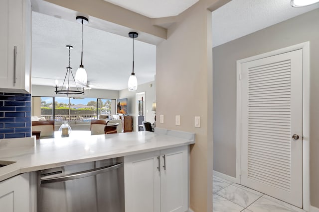 kitchen with pendant lighting, tasteful backsplash, white cabinets, dishwasher, and an inviting chandelier