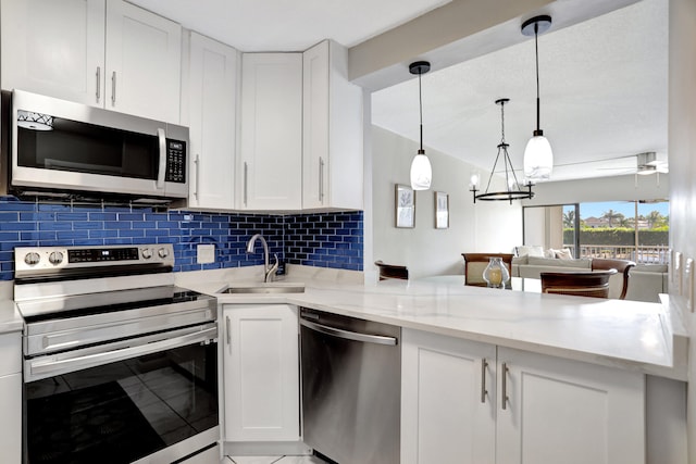 kitchen with sink, light stone counters, stainless steel appliances, an inviting chandelier, and decorative light fixtures