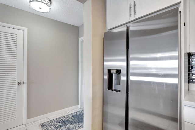 kitchen featuring high quality fridge, a textured ceiling, white cabinetry, and light tile floors