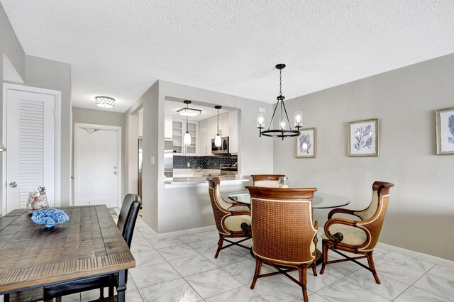 dining space featuring a textured ceiling, a chandelier, and light tile flooring