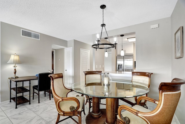 tiled dining room featuring a notable chandelier and a textured ceiling