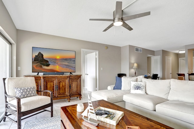 tiled living room with ceiling fan and a textured ceiling