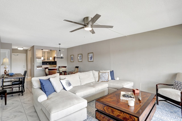 living room with a textured ceiling, ceiling fan with notable chandelier, and light tile flooring