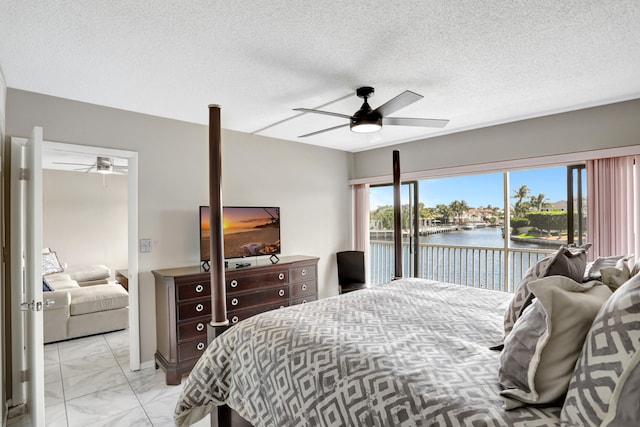 tiled bedroom featuring a water view, a textured ceiling, access to exterior, and ceiling fan