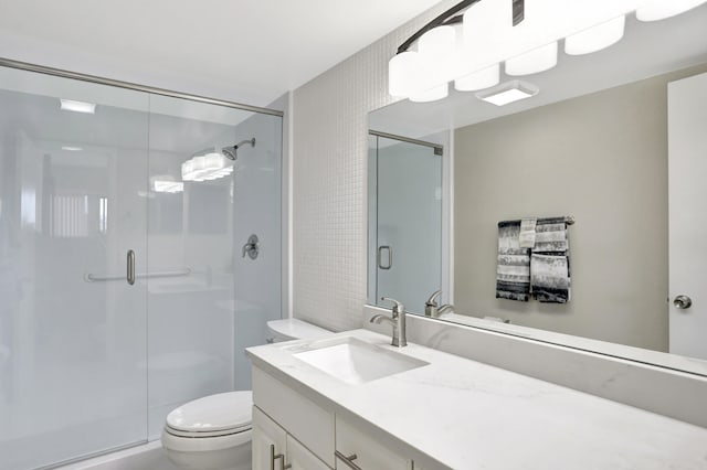 bathroom featuring toilet, large vanity, and an enclosed shower