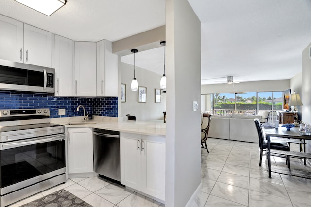 kitchen featuring hanging light fixtures, stainless steel appliances, ceiling fan, and white cabinetry