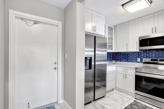 kitchen with light tile floors, white cabinets, backsplash, and stainless steel appliances