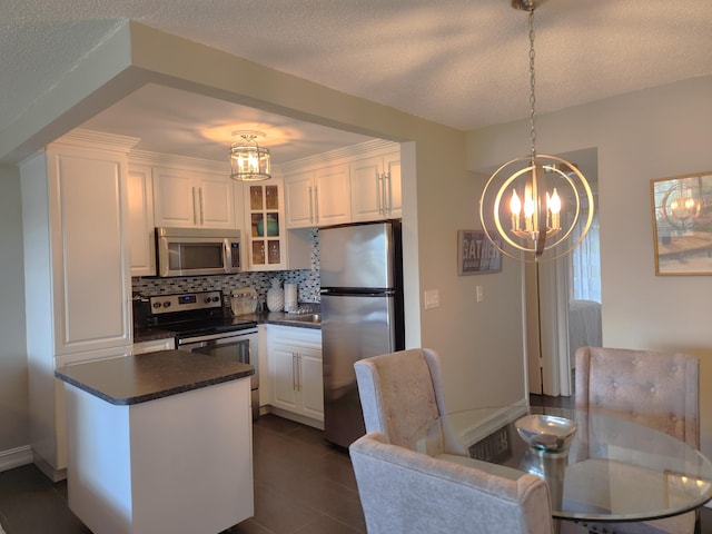 kitchen featuring white cabinets, appliances with stainless steel finishes, backsplash, and pendant lighting