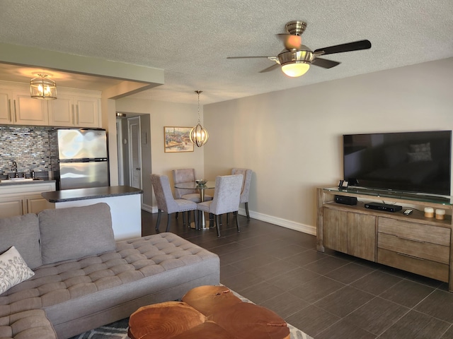 living room featuring sink, dark tile flooring, a textured ceiling, and ceiling fan with notable chandelier