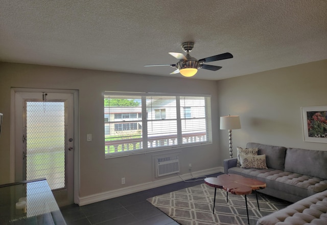 living room with a wall mounted AC, a textured ceiling, dark tile floors, and ceiling fan