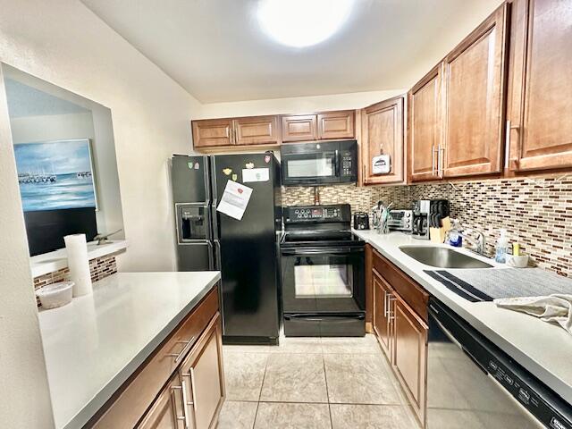 kitchen featuring tasteful backsplash, sink, light tile floors, and black appliances