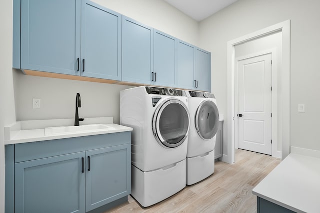 laundry room featuring sink, light hardwood / wood-style flooring, cabinets, and independent washer and dryer