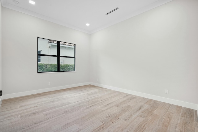 empty room with ornamental molding and light hardwood / wood-style flooring