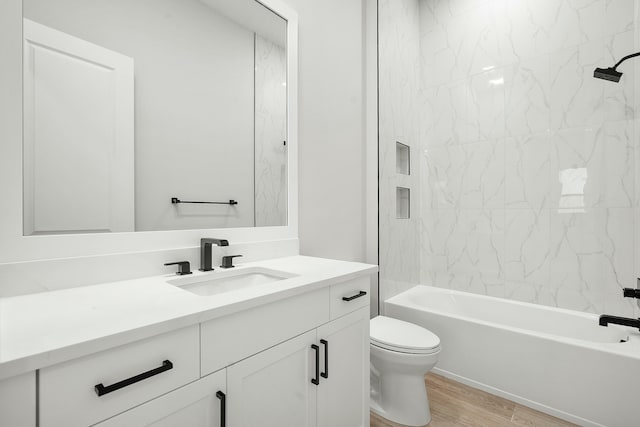 full bathroom featuring toilet, tiled shower / bath, wood-type flooring, and vanity