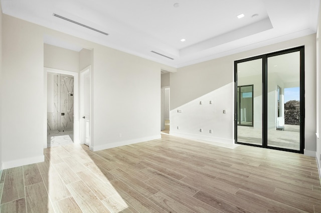 unfurnished room featuring a raised ceiling and light hardwood / wood-style floors