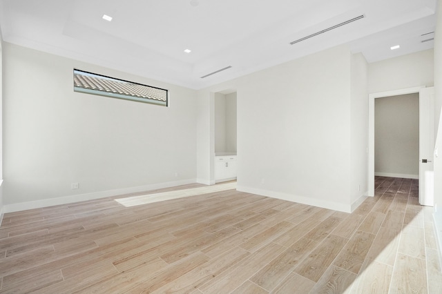 unfurnished room with a raised ceiling and light hardwood / wood-style floors