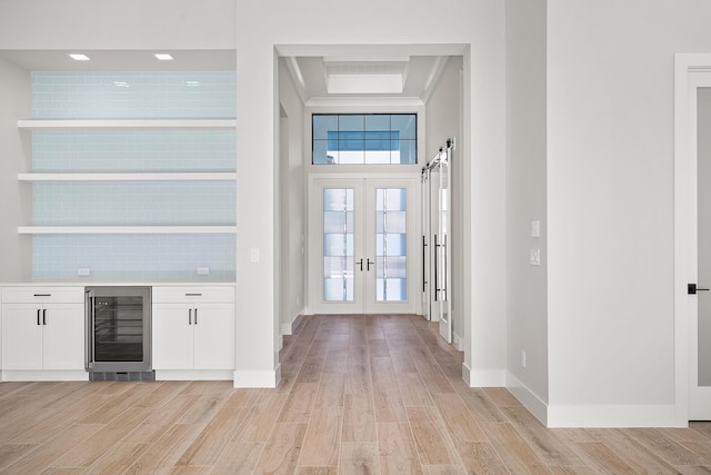 interior space featuring light hardwood / wood-style flooring, french doors, a barn door, and wine cooler