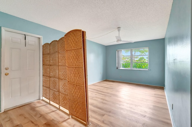 unfurnished room featuring ceiling fan, light wood-type flooring, and a textured ceiling