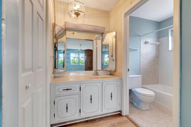 full bathroom featuring vanity, hardwood / wood-style flooring, tiled shower / bath combo, toilet, and a chandelier