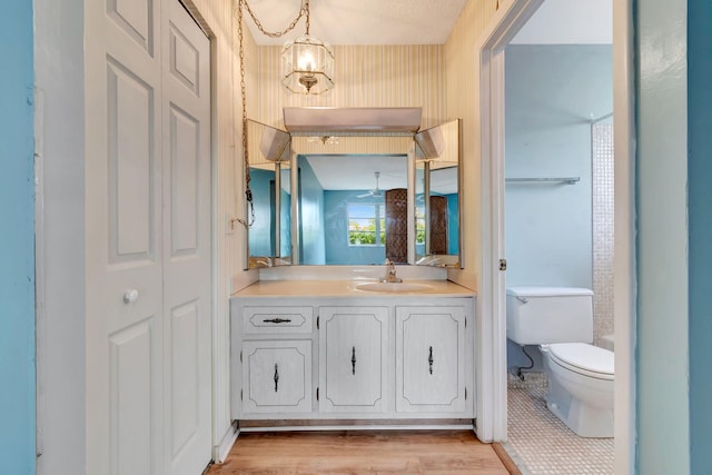 bathroom with hardwood / wood-style floors, vanity, toilet, and a chandelier