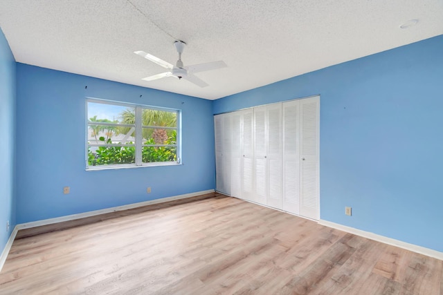 unfurnished bedroom with ceiling fan, a closet, a textured ceiling, and light wood-type flooring