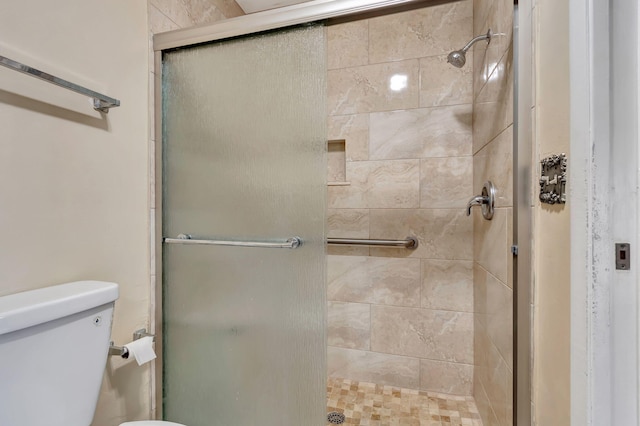 bathroom featuring a shower with door and toilet