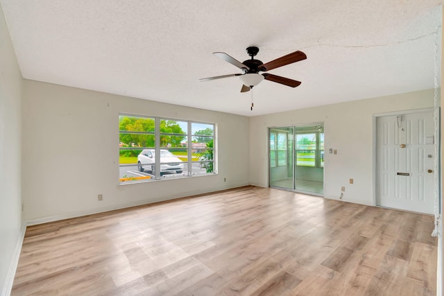 empty room with ceiling fan, light wood-type flooring, and a textured ceiling