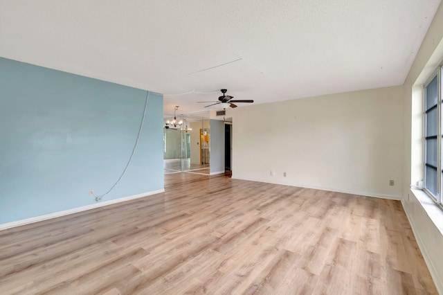 spare room featuring plenty of natural light, light hardwood / wood-style floors, and ceiling fan with notable chandelier