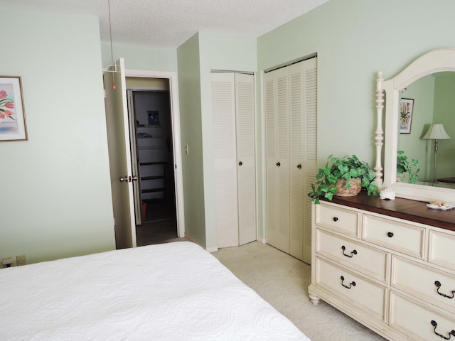 carpeted bedroom with a textured ceiling and two closets