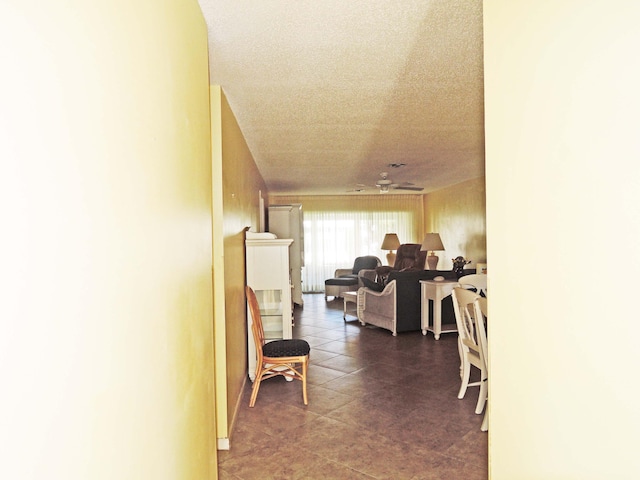 corridor with a textured ceiling and dark tile floors