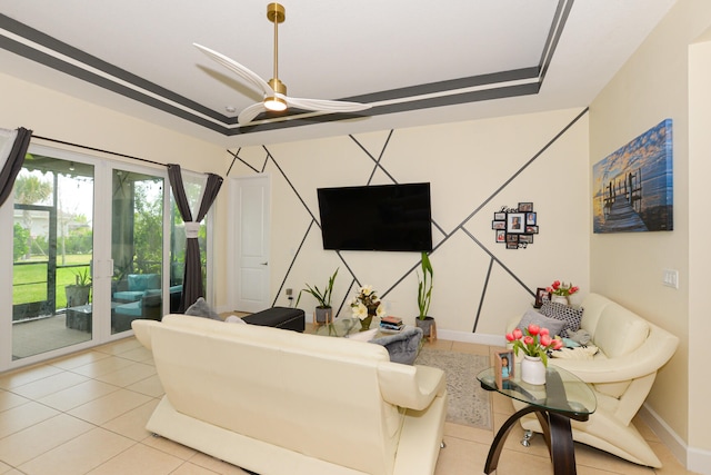 tiled living room with a raised ceiling and ceiling fan