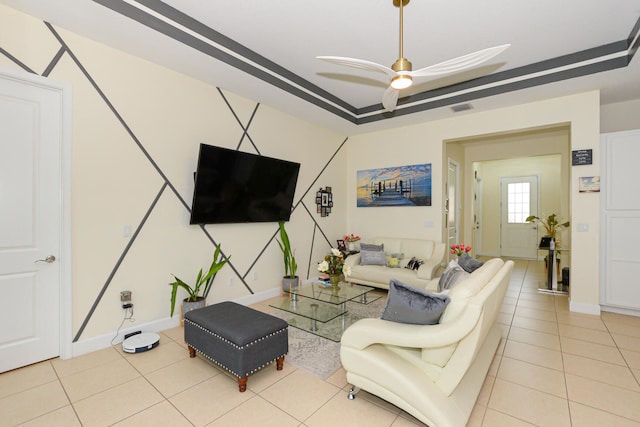 living room featuring light tile floors, a tray ceiling, and ceiling fan