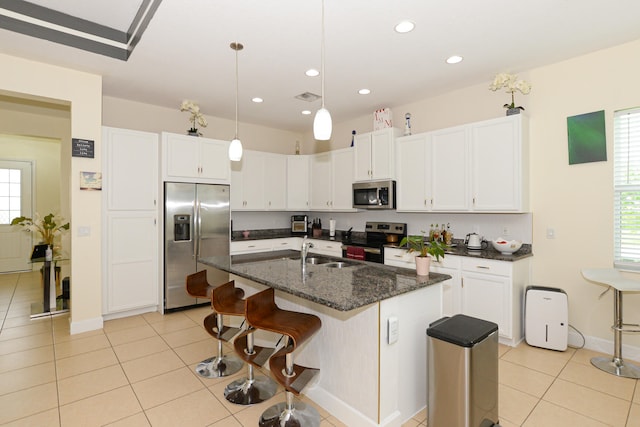 kitchen with light tile flooring, an island with sink, stainless steel appliances, a breakfast bar area, and pendant lighting