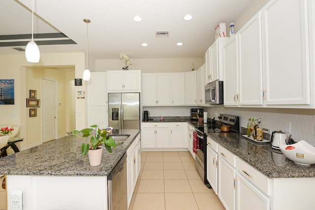 kitchen with decorative light fixtures, white cabinets, appliances with stainless steel finishes, and dark stone counters