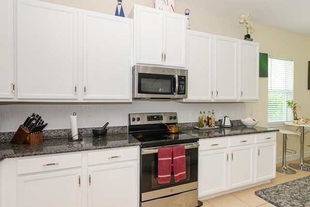 kitchen with white cabinets, stainless steel appliances, and dark stone counters