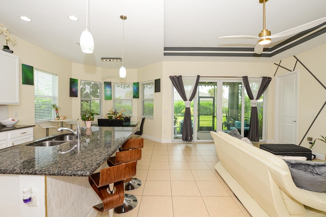 kitchen featuring dark stone countertops, white cabinets, plenty of natural light, and sink