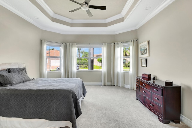 carpeted bedroom featuring crown molding, a tray ceiling, and multiple windows