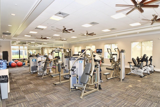 gym with a raised ceiling, ceiling fan, and dark colored carpet