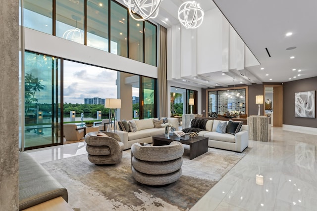 living room featuring a notable chandelier, recessed lighting, marble finish floor, and a towering ceiling