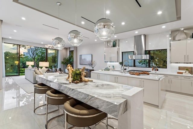 kitchen with modern cabinets, an island with sink, white cabinetry, recessed lighting, and island range hood