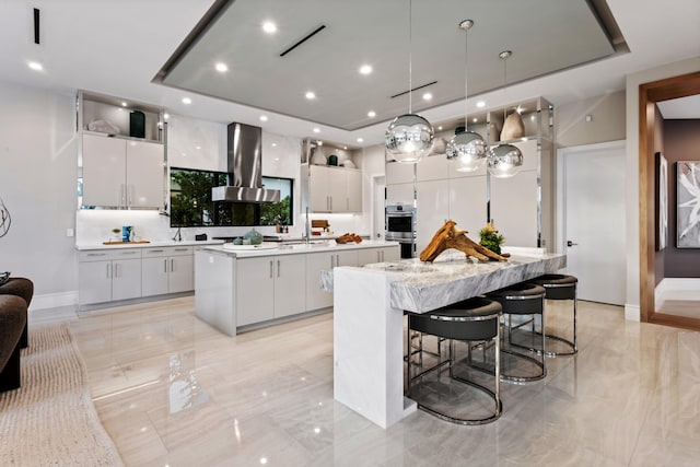 kitchen with a raised ceiling, a large island, double oven, and range hood