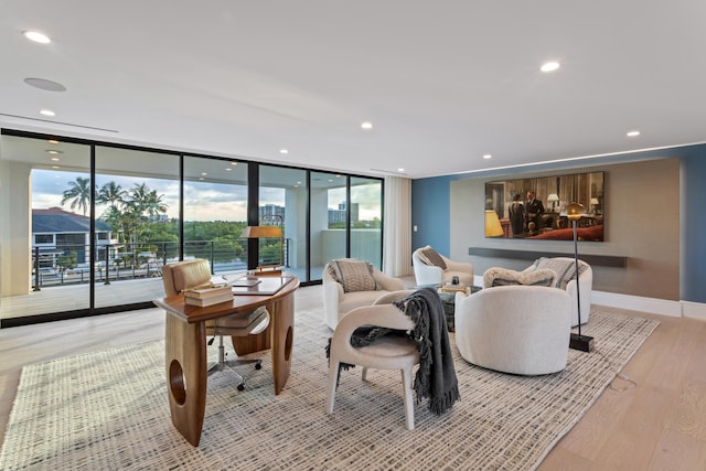 living room featuring light wood finished floors, recessed lighting, floor to ceiling windows, and baseboards