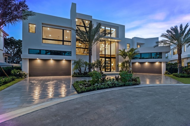 contemporary home with decorative driveway, an attached garage, and stucco siding