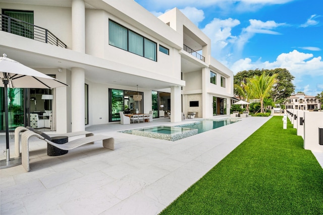 back of house with stucco siding, a patio, and a pool with connected hot tub