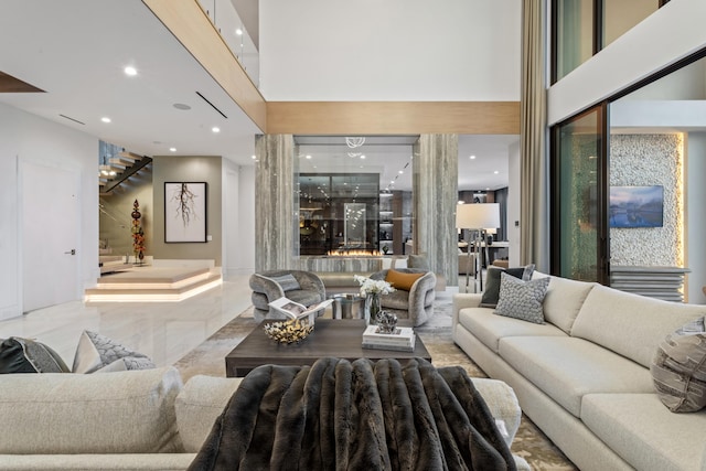 living room featuring recessed lighting, marble finish floor, a towering ceiling, and stairs